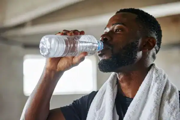 Image of man drinking water to improve hydration Nuneaton after work out.